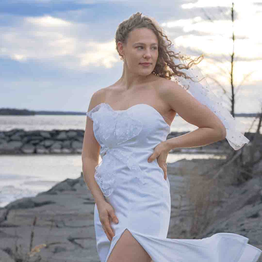 Bridal photography- portrait of a bride standing elegant on rocks with the sea ocean behind her