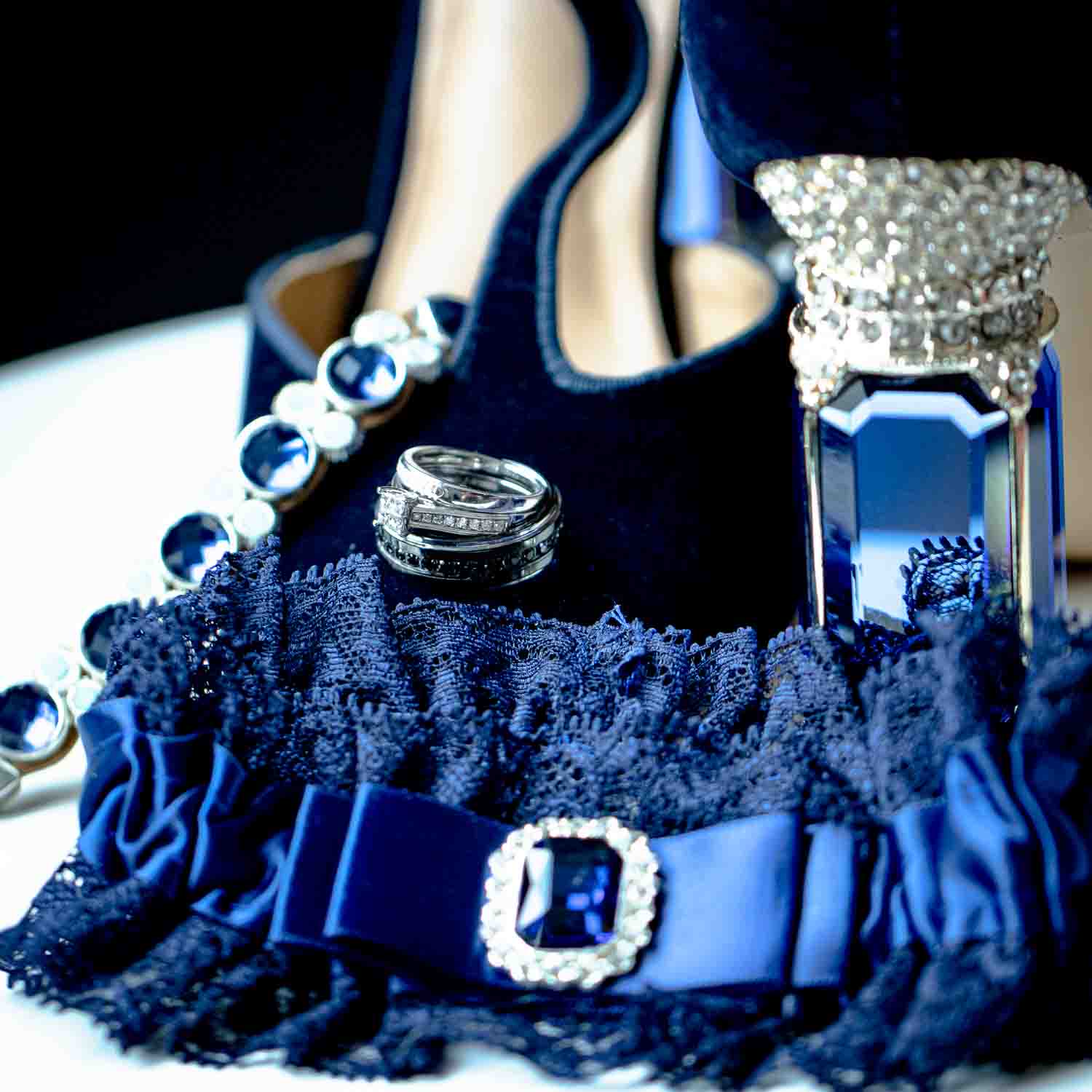 Wedding photography. Bridal details. Deep blue garter with sapphire and rhinestone accent. Sapphire and white gold bracelet. Navy Blue pumps with sapphire and crystal heel. Engagement ring and wedding bands. Something old, something new, something borrowed, something blue and a sixpence in her shoe. 10 best photographers near Lake George, NY.  Wedding Photographer. Albany, Lake Luzerne, NY.