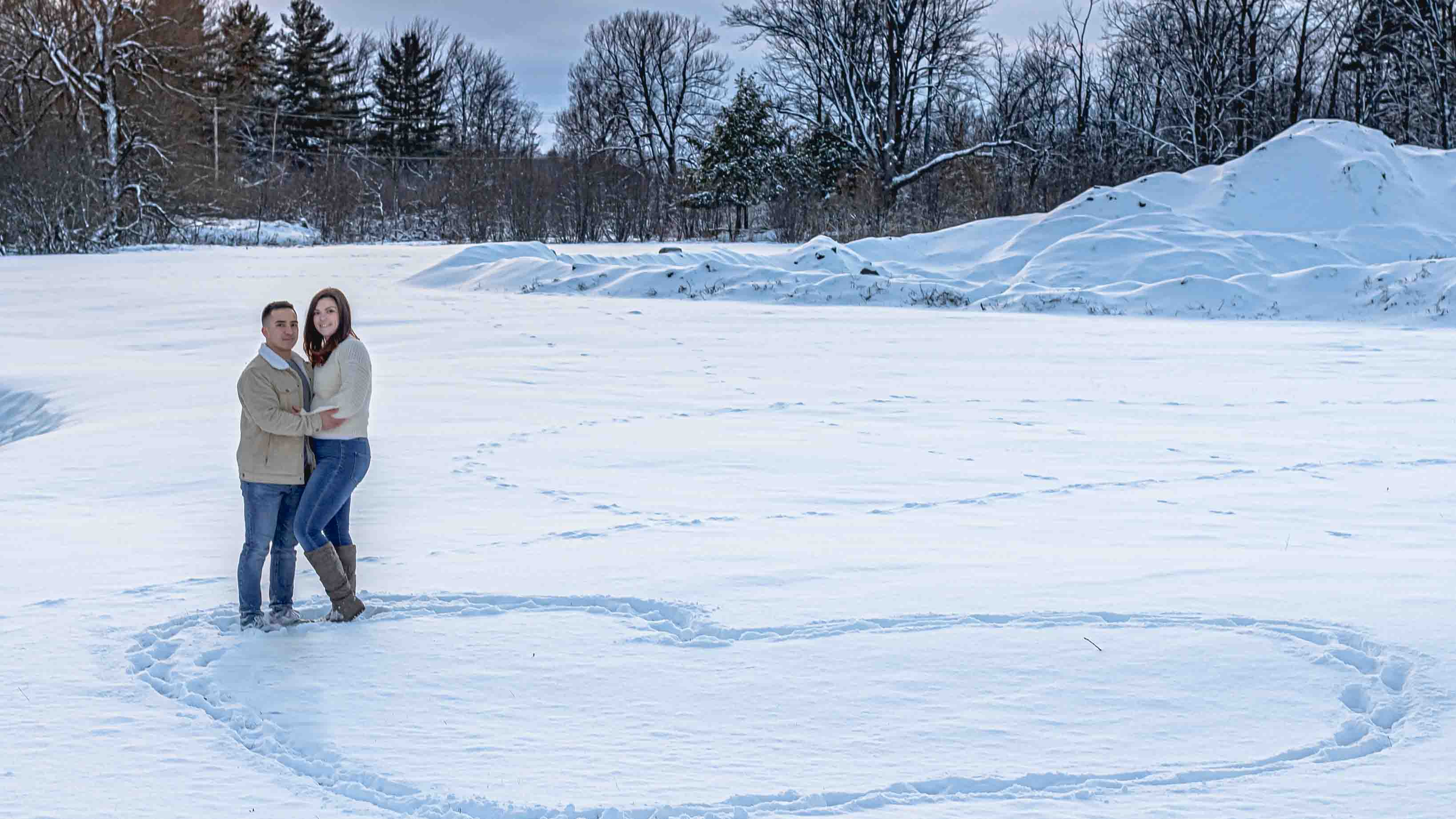 couples portrait winter snow covered field heart drawn in the snow Watertown NY Fort Drum Photographer. Winter Wedding Photographer. 10 best wedding photographers in Burlington VT.