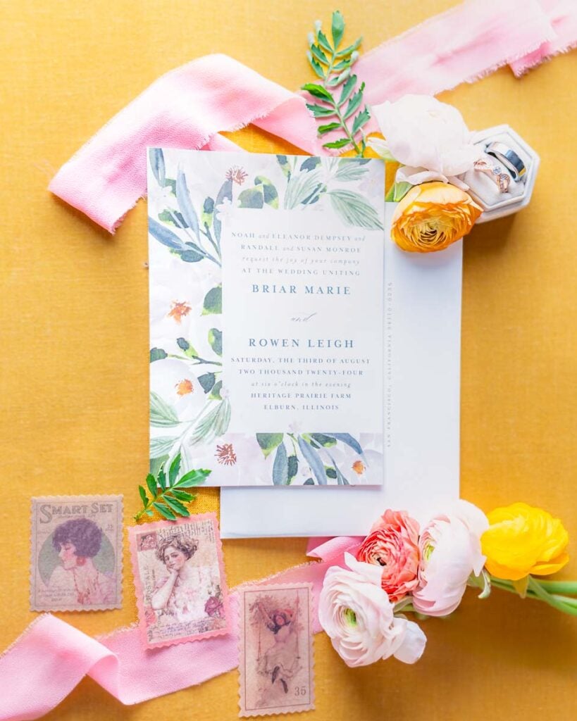 Vibrant wedding invitation setup with pink and yellow accents on a bright yellow background.
