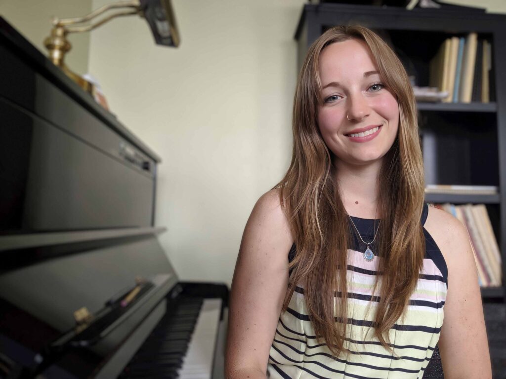 Kylie B smiling at camera while playing the piano, enhancing the wedding's elegant atmosphere.