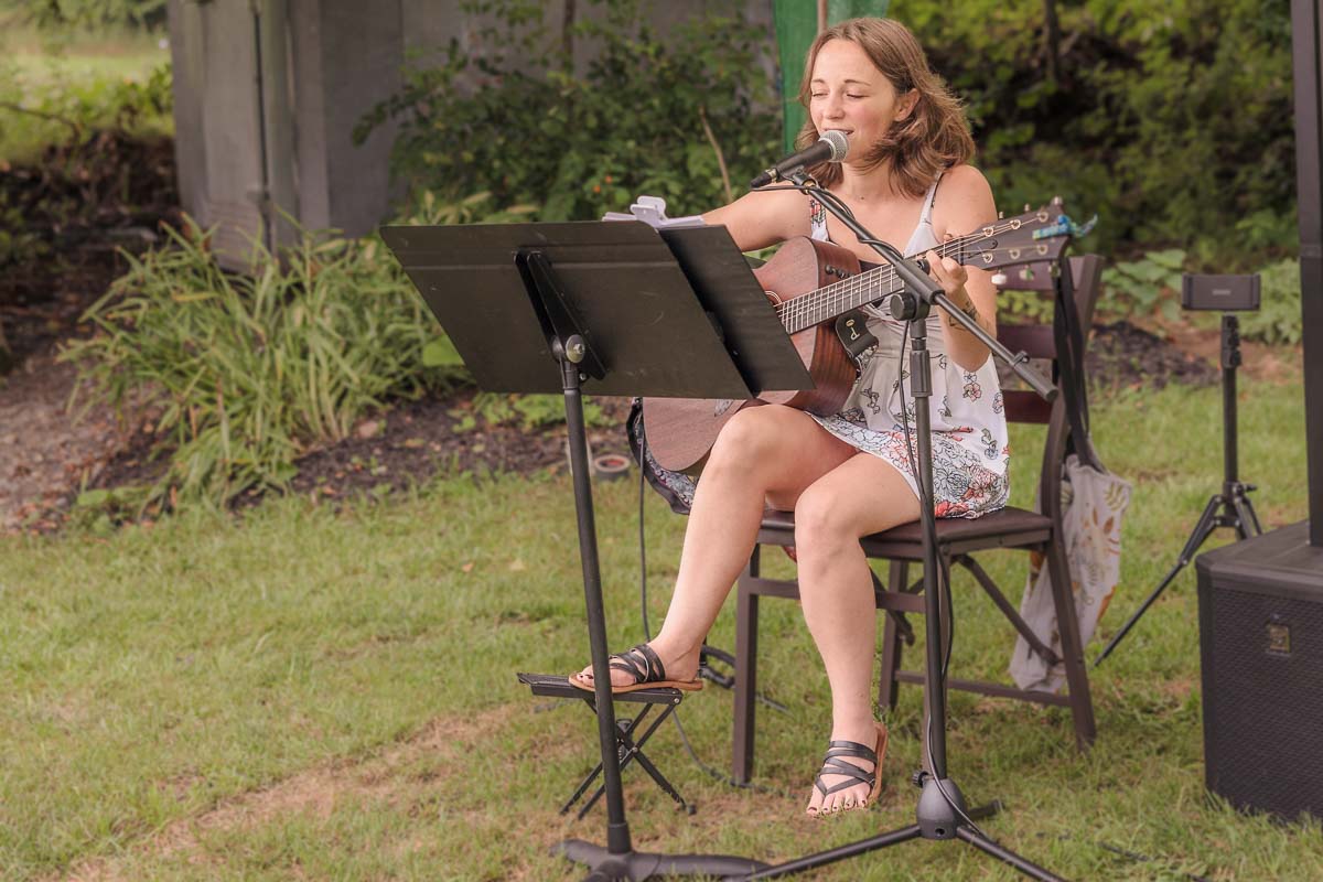 Live Music For Wedding to elevate ceremony and entertainment. Image depicts a Female guitarist performing at an intimate, outdoor wedding ceremony.