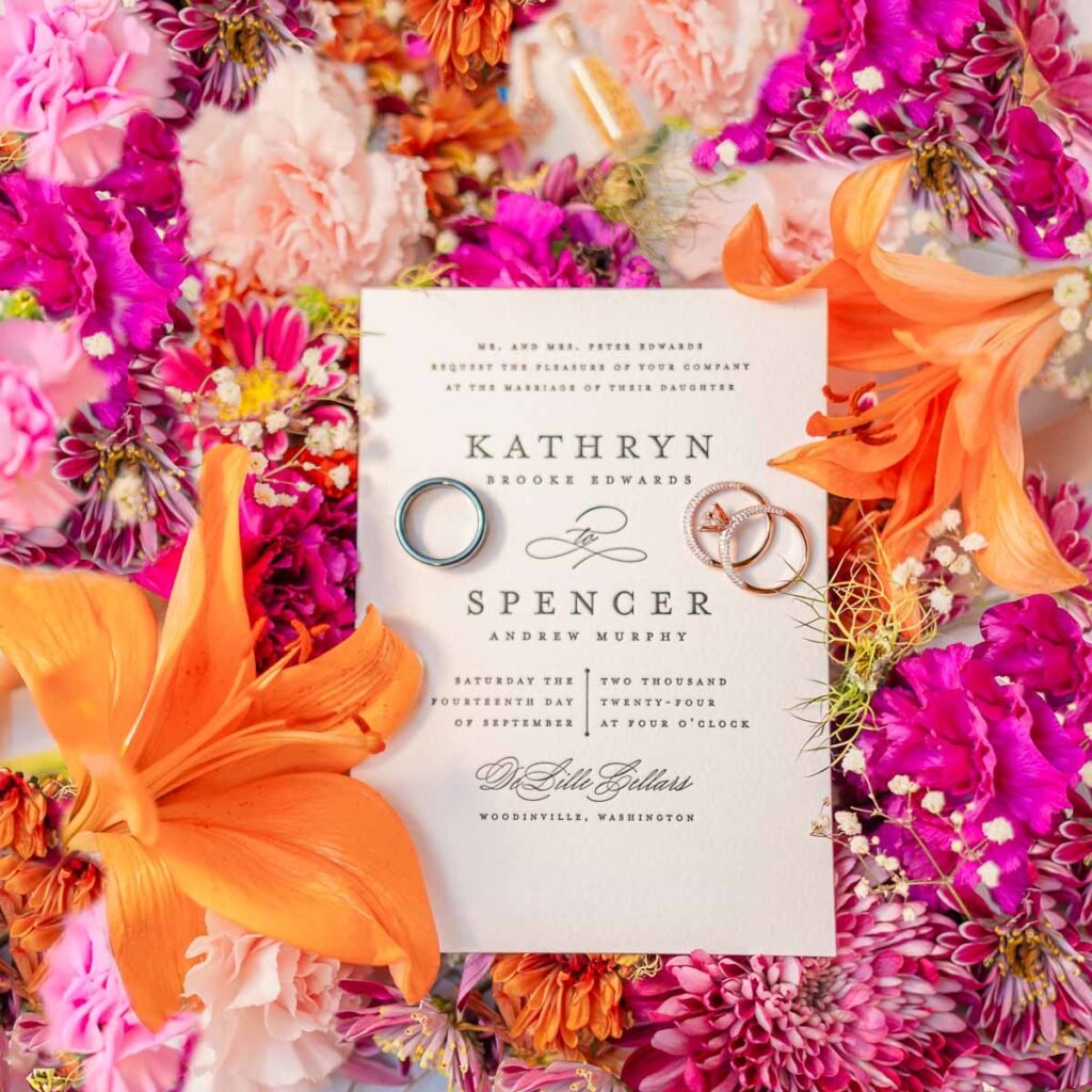 Kathryn and Spencer's elegant wedding invitation amidst a colorful array of summer flowers.