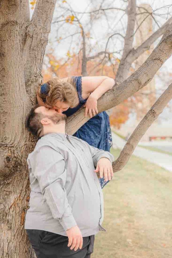 Hanna kissing Shawn while perched on a tree during their Kansas City engagement pictures.
