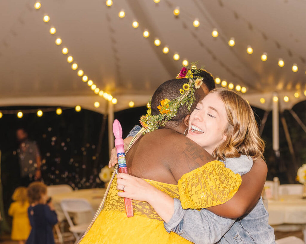 Danaya shares a heartfelt hug with a guest while holding a bubble wand during her Knoxville wedding reception.