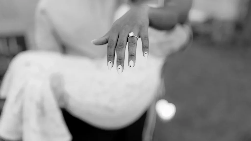 Closeup of engagement ring on bride’s hand with custom black and white manicure