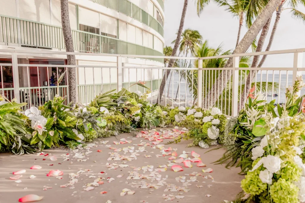 Oceanfront wedding ceremony aisle lined with lush greenery, white hydrangeas and rose petals at Kaimana Beach Hotel