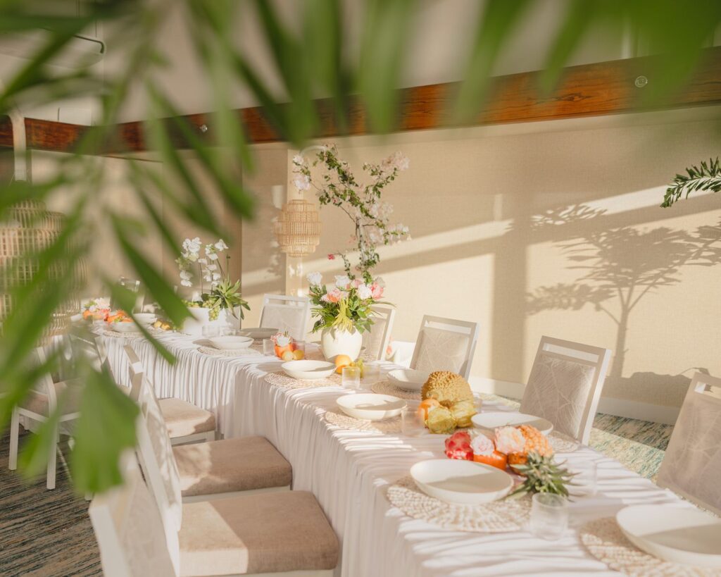 Tropical wedding reception table framed by palm fronds in warm afternoon light at Kaimana Beach Hotel
