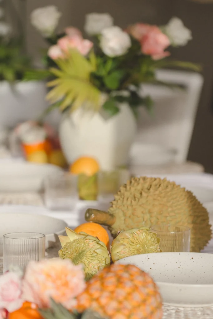 Tropical fruit and garden rose centerpiece with pineapple, citrus and durian on a Hawaii wedding reception table