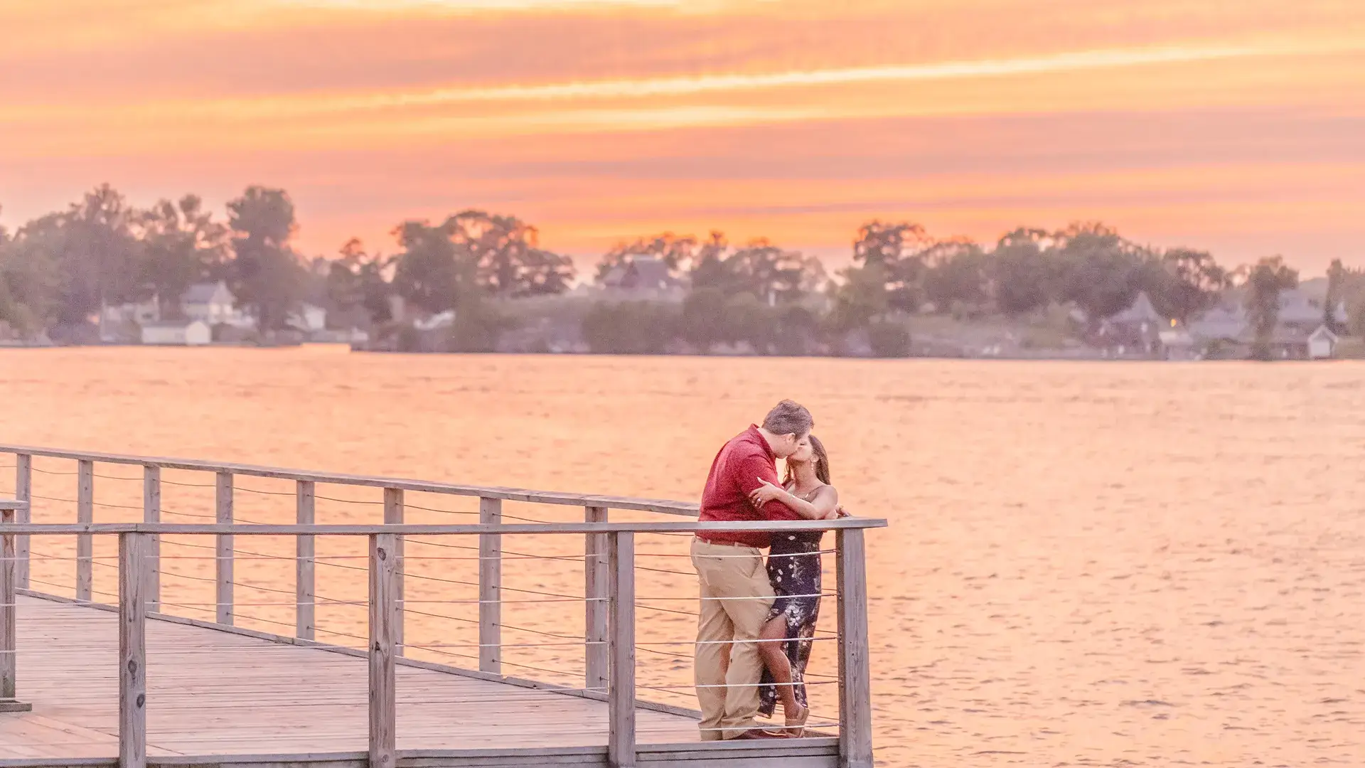 Engaged couple kissing at sunset on a dock in Alexandria Bay, New York