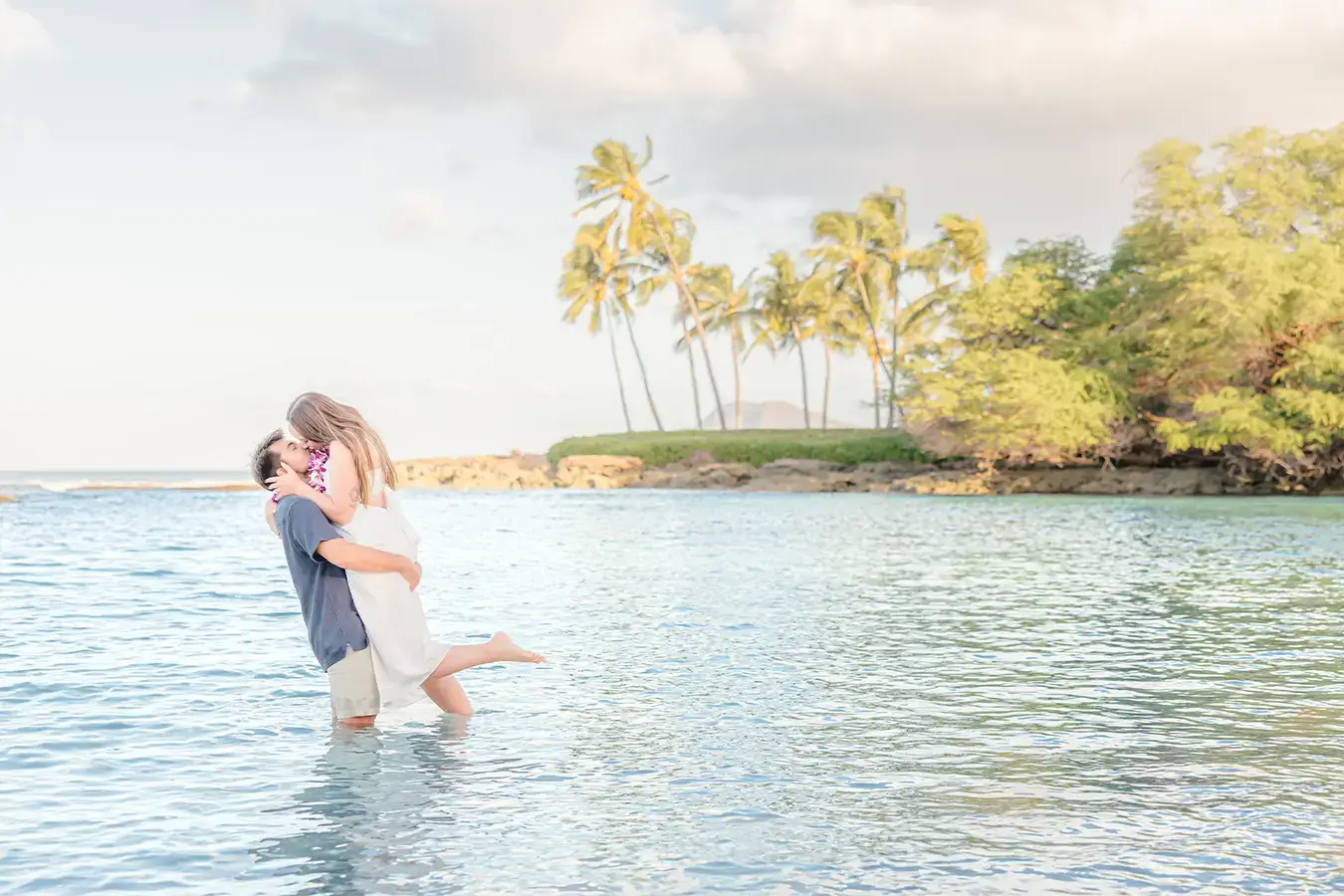 Secret Proposal by Grand Gestures proposal experiences. Fiancé lifts his partner in the ocean during their Honolulu engagement session at Paradise Cove.
