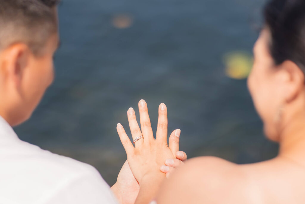 Engagement Proposal planner, Groom holds bride’s hand to admire her engagement ring after a lakeside destination proposal at Lake Ontario