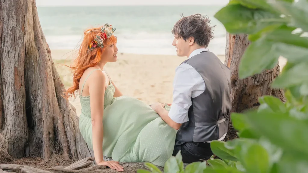 Couple sitting beneath beach trees looking at each other