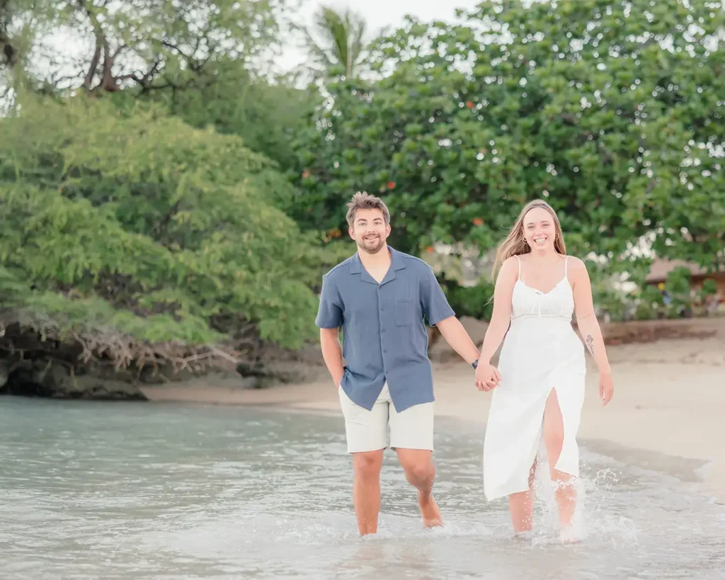 Couple walks barefoot through the surf during their Honolulu engagement session Title: Barefoot in the Surf at Sunrise