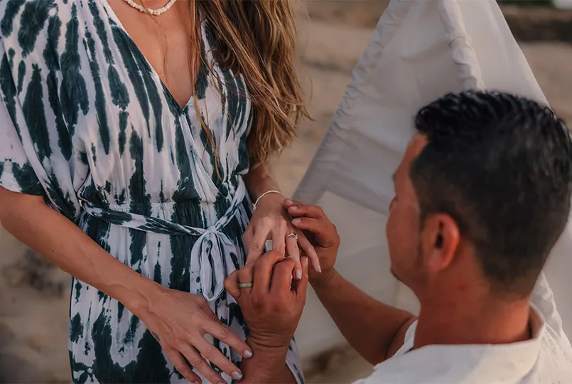 Cheyenne places a ring on Loraine’s finger in front of a white teepee on the beach during their recreated Hawaii proposal.