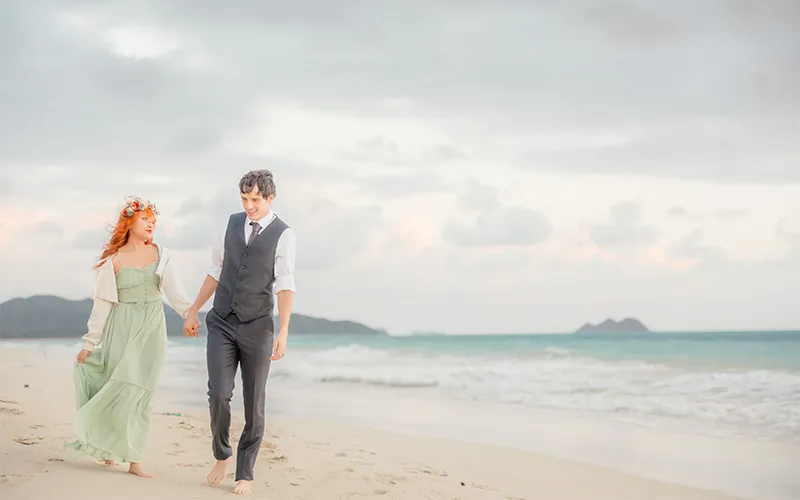 hawaii proposal packages by surprise proposal photographer, LT² Photography. Couple holding hands walking barefoot along Waimanalo Beach during an engagement session