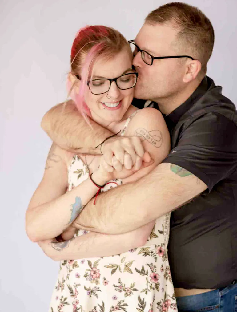 oahu proposal photographer. Couple sharing a joyful embrace during an indoor couples photoshoot, with the man kissing his partner on the cheek as she smiles.
