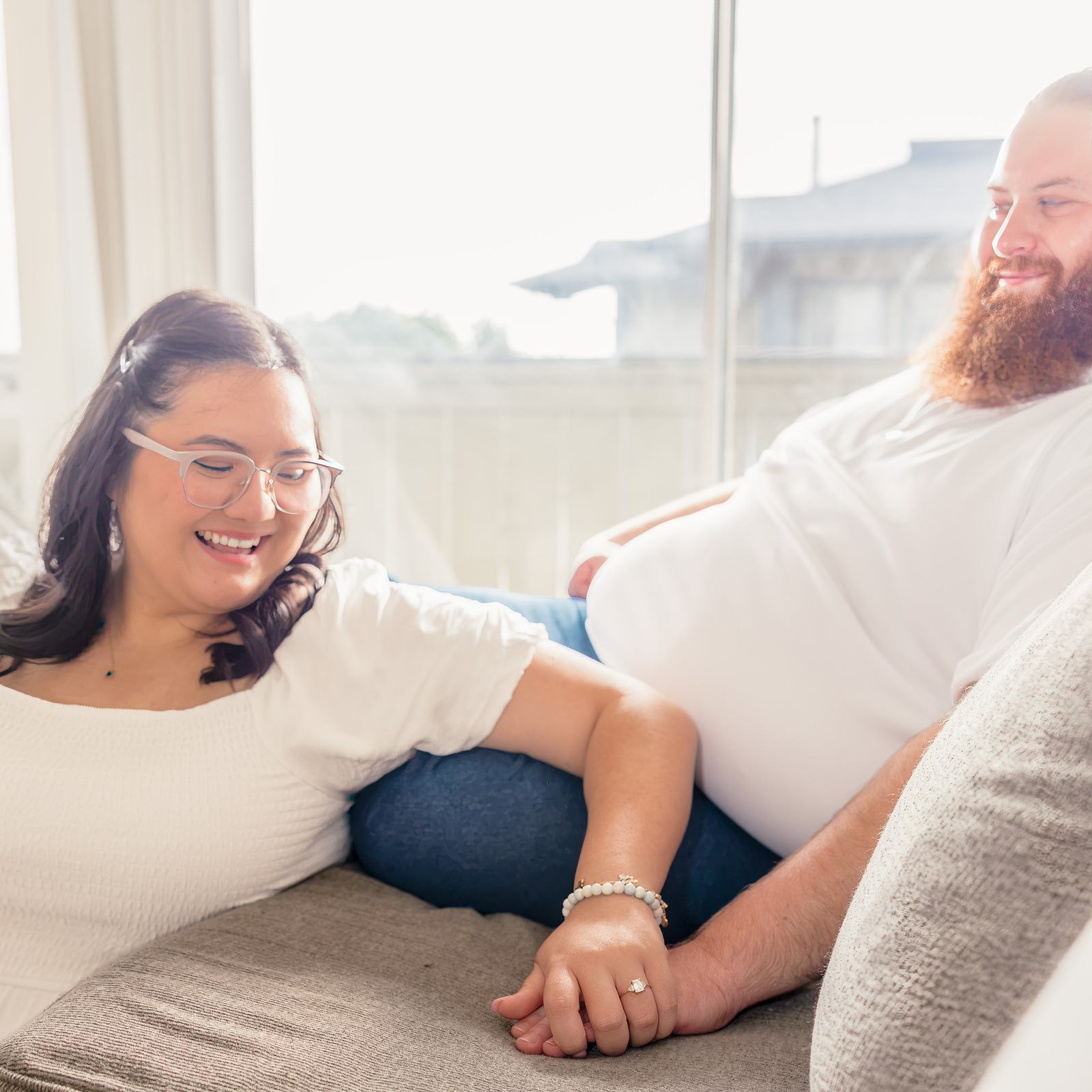 Hope laughs as she and Dean lie on the couch holding hands, her engagement ring showing.