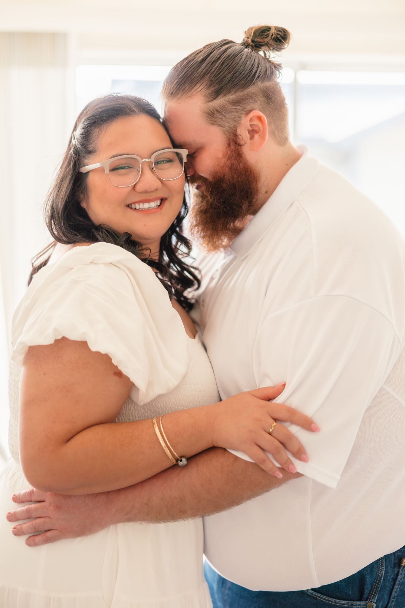 Hope smiles at the camera while Dean leans his forehead against her head, his arms wrapped around her.