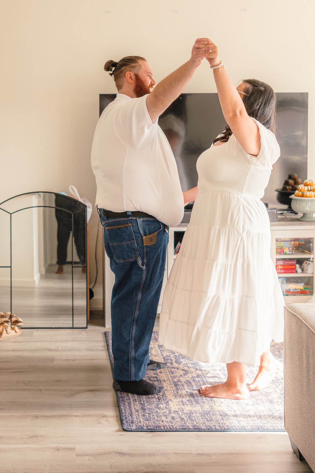 Dean twirls Hope in their living room as she smiles, her white dress swaying.
